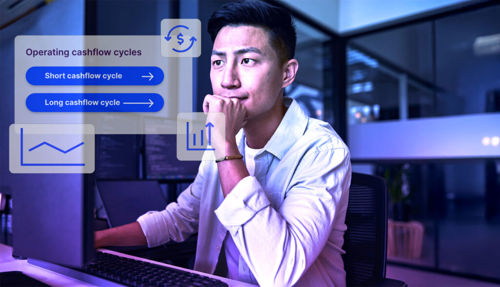 A young man in a white shirt sits at a desk, looking thoughtfully at a computer. The modern office has glass walls and multiple monitors. A blue-tinted overlay features 'Operating cashflow cycles' with buttons for 'Short cashflow cycle' and 'Long cashflow cycle,' along with icons of a dollar sign and a bar chart.